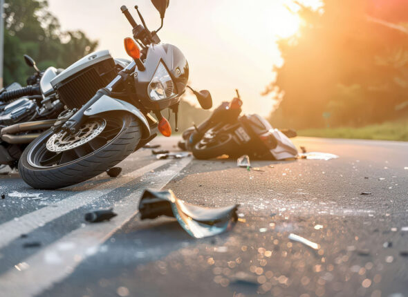 A motorcycle lies damaged on the asphalt, surrounded by debris,
